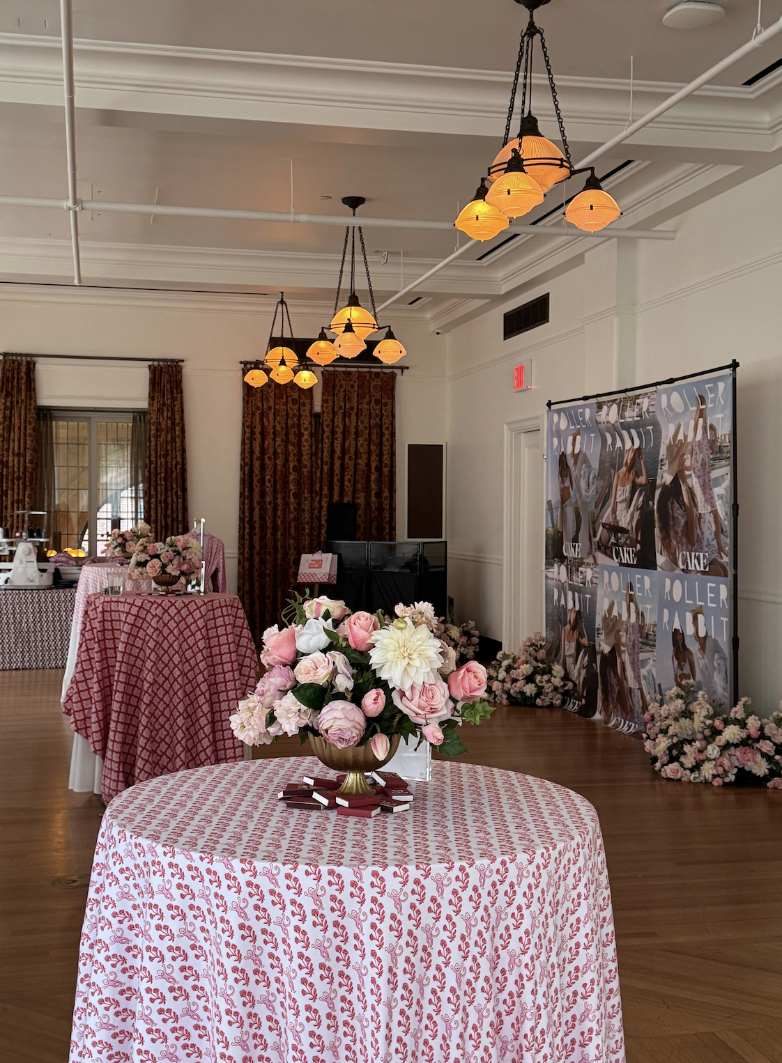 CAKE x Roller Rabbit Mother’s Day event space at Nine Orchard with pink floral arrangements, patterned tables, and branded photo backdrop.